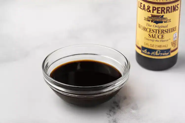 Rich Worcestershire sauce in a glass bowl with a bottle of Lea & Perrins Worcestershire sauce in the background.